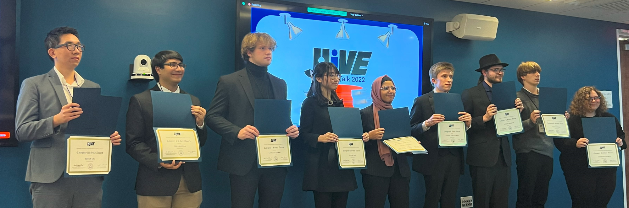 ten J.LIVE winners on stage with their award certificates