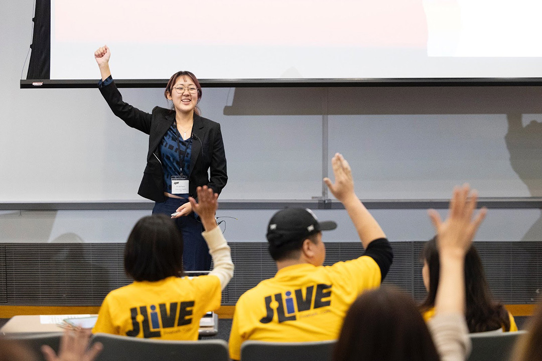 Rachel Kwon smiling and fist bumping at the front of a room