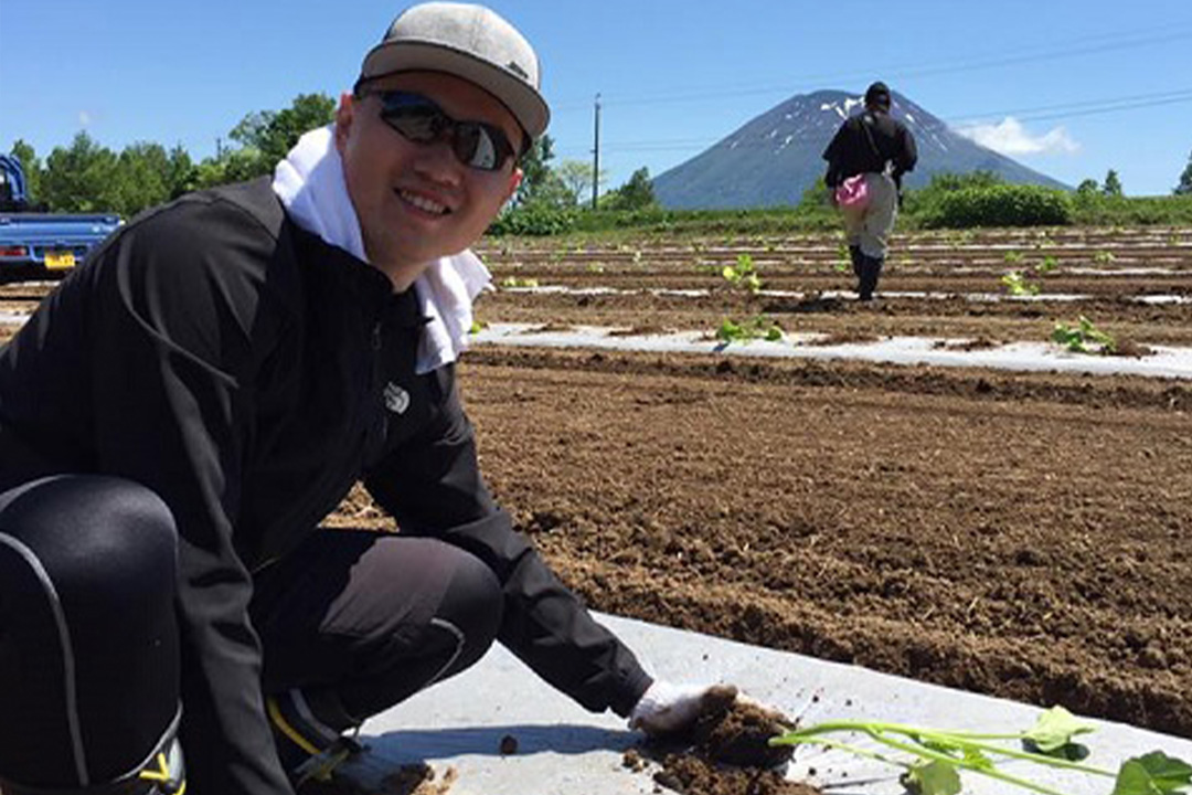 GW East Asian Languages and Literatures Alumni Yanru Wu kneeling while putting a plant in the ground
